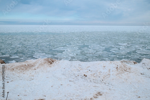 Frozen Sea And Icy Shoreline With Snow-Covered Beach And Broken Sea Ice Under Overcast Sky