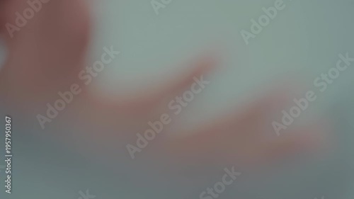 Blurry image showing pinkish and blue-gray hues, likely human form