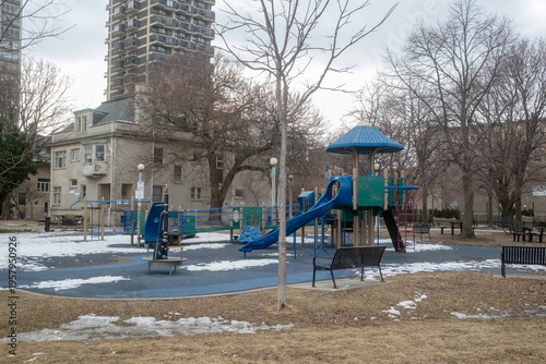 Empty Urban Playground in Winter With Blue Slide and Benches Near Residential Buildings