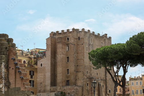 Photography A wide view of the 13th-century Torre dei Conti standing near the Via dei Fori Imperiali and the Roman Forum, featuring classic brick masonry and surrounding stone pine trees under a clear blue sky