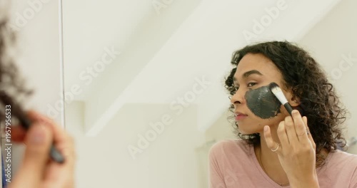At bathroom mirror nonbinary adult applying charcoal mask with brush for even coverage copy space