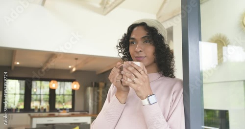 Non-binary adult holding ceramic mug in home doorway, inhaling aroma, smiling at camera, copy space