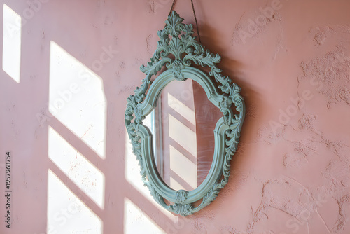 Vintage ornate baroque mirror with turquoise frame hanging on pink wall