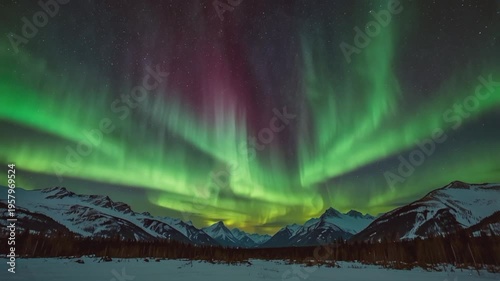 A stunning view of the Aurora Borealis (Northern Lights) over the snowy mountains. The lights dance in a dramatic mix of bright green and reddish purple.
