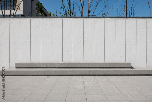 White vertical striped wall with gray concrete steps in a modern outdoor plaza setting