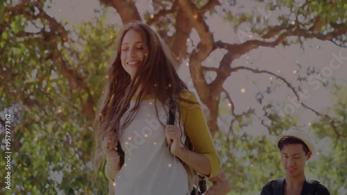 Lead woman fixing straps on park path, camera rising, sparkling particles over group, education