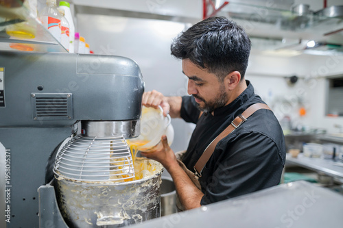 Cuadro en lienzo Latino baker pouring ingredients into a stand mixer