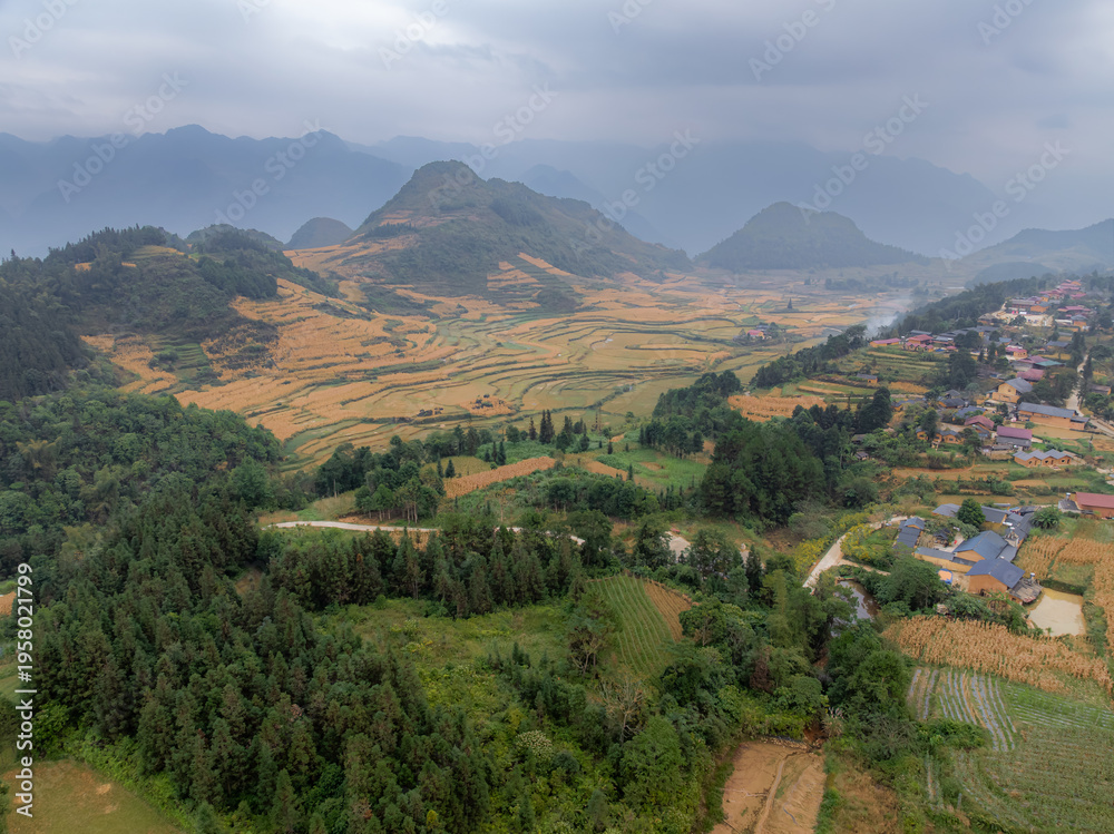 Obraz premium Aerial view of a rural village in Quan Ba, Ha Giang, Vietnam, nestled among mountains and rice terraces. The houses are built in traditional style, blending with nature.