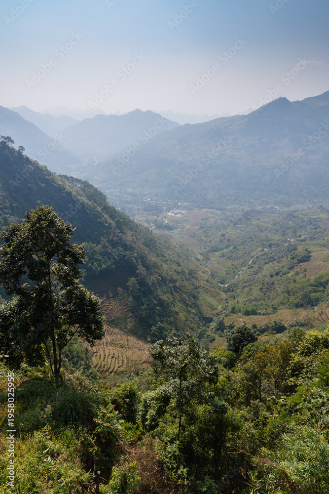 Fototapeta premium A scenic view of the mountains and valleys in Ha Giang, Vietnam. The landscape showcases the natural beauty of the region, with lush greenery and terraced fields.