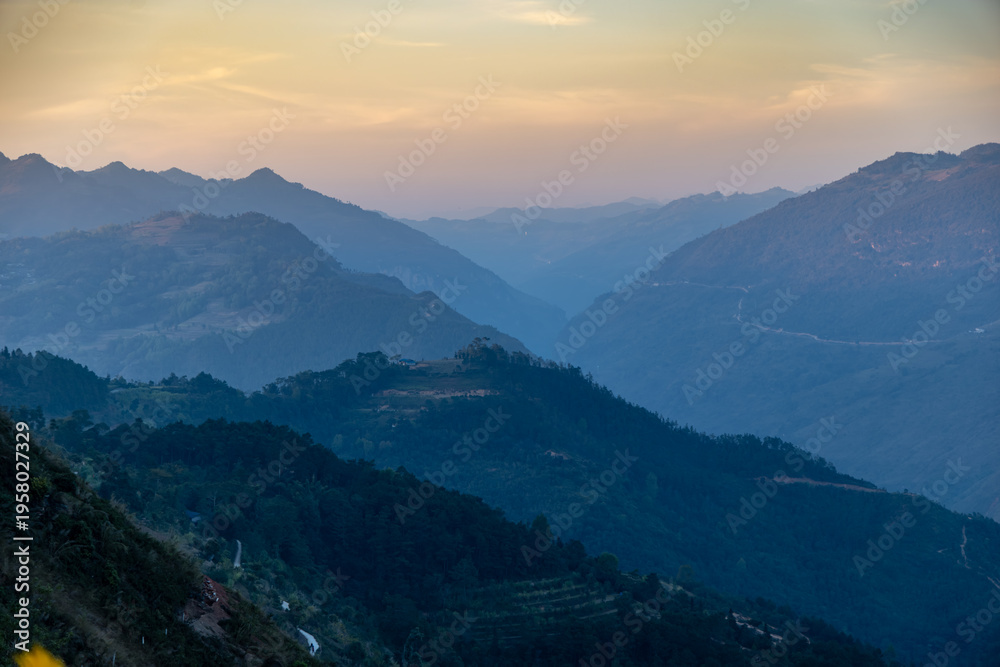 Fototapeta premium A scenic view of the mountain range in Dong Van, Ha Giang, Vietnam, showcasing the natural beauty and winding roads through the landscape at dusk.
