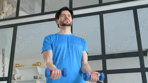 Portrait of active determined sporty fit man exercising dumbbell biceps curl, strengthening upper arm, expressing determination and confidence while working out at home.