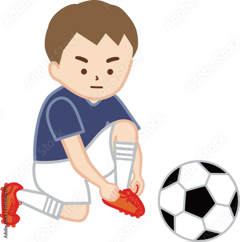 しゃがんでサッカーシューズの紐を結ぶ男の子