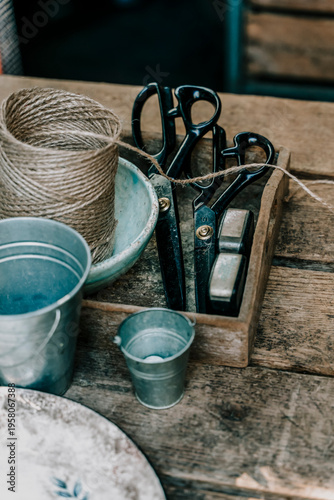 Rustic wooden table with vintage gardening tools, twine and buckets. High-angle flat lay view of a wooden box containing retro scissors and accessories for garden work