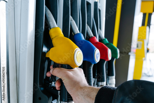 Fuel pump nozzles hanging at a modern gas station during a period of high oil prices. A conceptual photography showcasing the global energy crisis, increasing gasoline costs