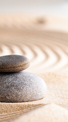 Stacked stones on smooth sand with circular patterns in background during daylight hours