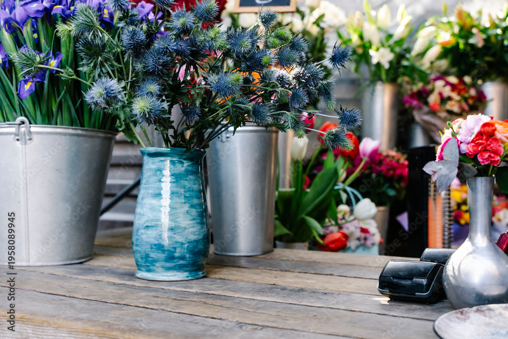 Fototapeta premium Cozy and authentic rustic flower shop counter with dried lavender and vintage gardening tools. An intimate workshop scene showing a hand tying a flower bouquet on a weathered wooden table with antique