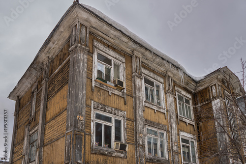 Fényképezés House with peeling paint and weathered wooden facade under overcast sky, low ang