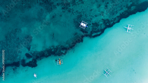 Foto Top-down aerial view of traditional outrigger boats anchored on a vibrant coral