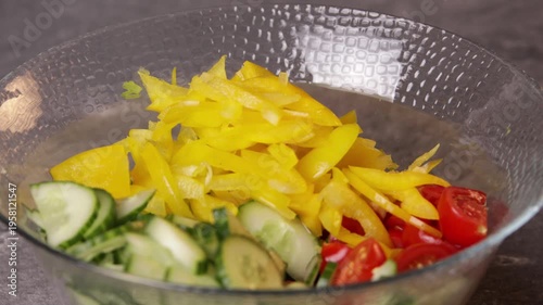 A cook transfers sliced yellow peppers to a bowl to prepare a salad. Close-up.