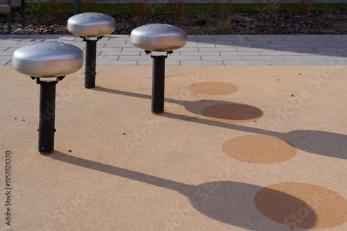 Metal tongue drums standing on playground surface.
