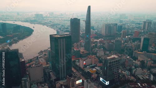 sunset over modern Ho Chi Minh city skyline and Saigon river, financial downtown district with high-rise skyscraper towers, Vietnam aerial drone view 4k