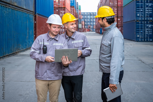 Engineer industrial workers males discussing logistics using laptop and tablet in shipping container yard