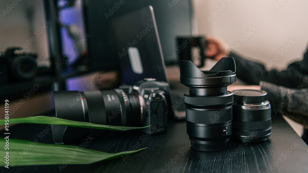 Naklejka premium Professional camera equipment and laptop on a dark wooden desk, ready for creative work