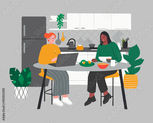 Two women in a modern kitchen one working on a laptop