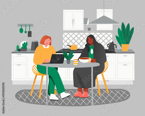 Two women enjoying coffee and working on a laptop in a kitchen