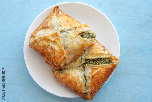 Food background with Cheese Spinach Puff Pastry on ceramic plate over blue wood surface.