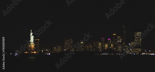 La icónica estatua de la Libertad iluminada de noche. Imagen tomada desde el ferry a Staten Island con el skyline de New Jersey al fondo en noviembre de 2019.