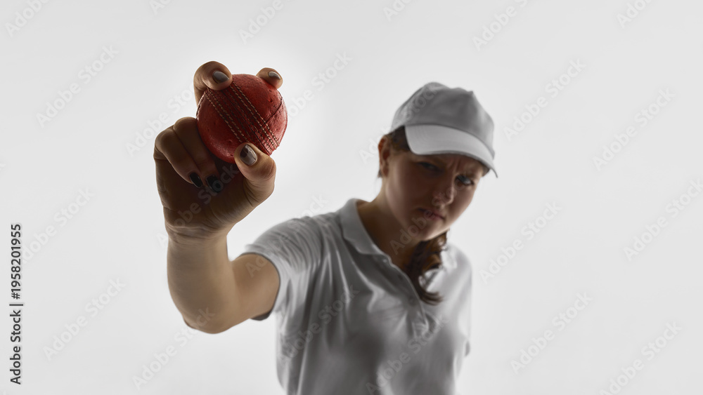 Fototapeta premium Female cricket player holding cricket ball toward camera isolated on white background. Concept of sports advertising banners, promotional campaigns, brand messaging, copy space design.