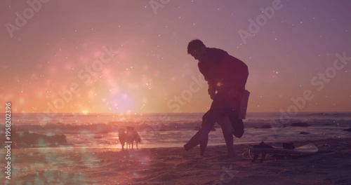 Surfer pulling wetsuit off after surfing on sunset beach, lens flare showing surfboard and dogs