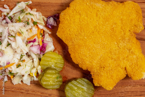 Food background with chicken schnitzel, pickled cucumber, sauerkraut on wooden platter.
