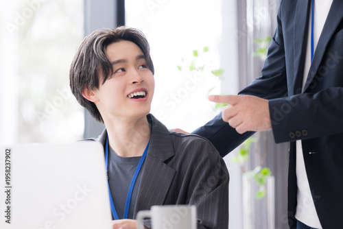 Valokuva 会社の仕事中に上司に励まされる新卒などの新入社員の爽やかなイメージ　その調子！仕事頑張ってね！OJTで先輩に指導を受ける若手社員の成長と教育のビジネスシーン