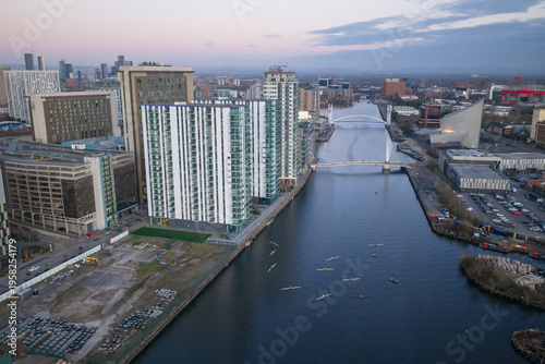 Obraz na płótnie Aerial image of rowers on the Manchester Ship Canal at dusk, featuring the modern architecture of Salford Quays and MediaCityUK