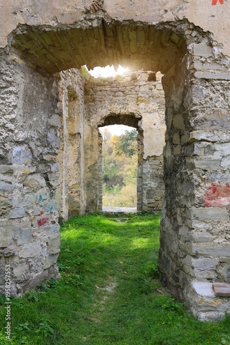 Fotografie Sunlight streams through ancient stone archways of a crumbling ruin overgrown wi