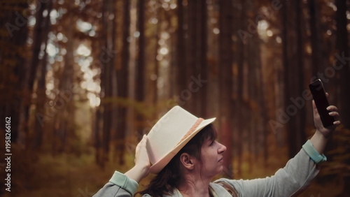 Fotografía brunette woman picks up the signal on the phone in the forest in autumn, out of