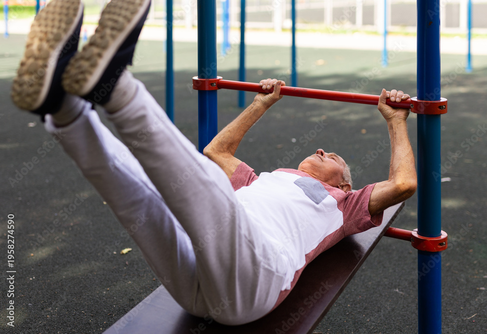 Obraz premium Old man doing leg raise exercise outdoors