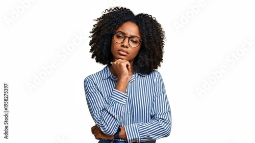 A thoughtful woman in a blue striped shirt looks up with a contemplative expression .