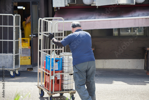 都市の飲食店に食材を運ぶ男性作業員の姿