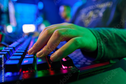 Closeup of Gamer Hand Typing on RGB Mechanical Keyboard in Dark Game Room Environment