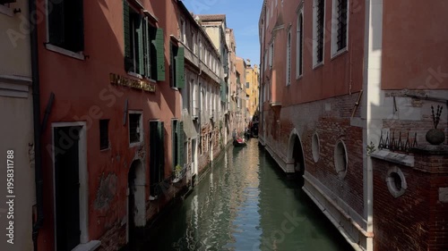 Narrow Venetian canal with gondola and pastel facades