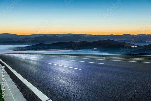 Fotografie Modern high speed highway passing through foggy mountain landscape at twilight