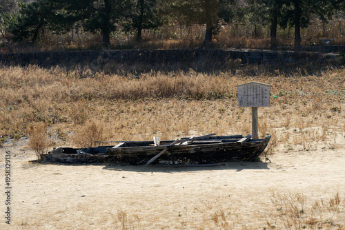 Foto Close-up view of a weather-beaten abandoned wooden boat relic on dry sandy ground on a sunny day in Japan