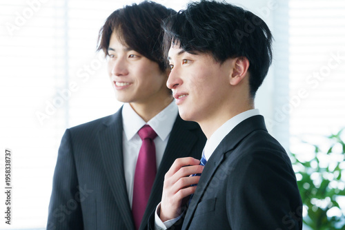 オフィスで並んで立つ若い2人の日本人男性の横顔