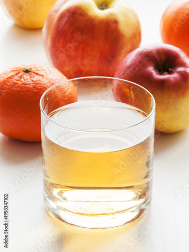 Glass of fresh apple and orange mixed vitamin juice on table with fruits, sweet healthy beverage.