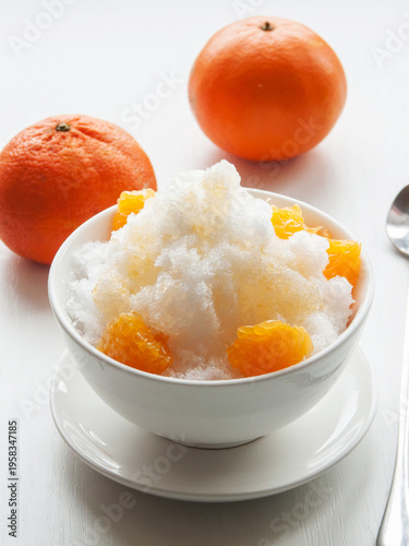 Shaved ice Kakigori granita fruit dessert for summer made of ice with juice sauce in bowl on table.