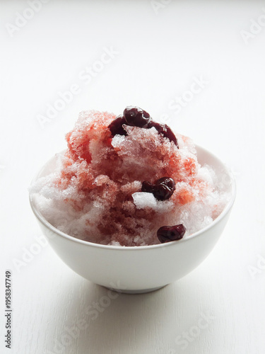 Shaved ice Kakigori granita berry dessert for summer made of ice with juice sauce in bowl on table.