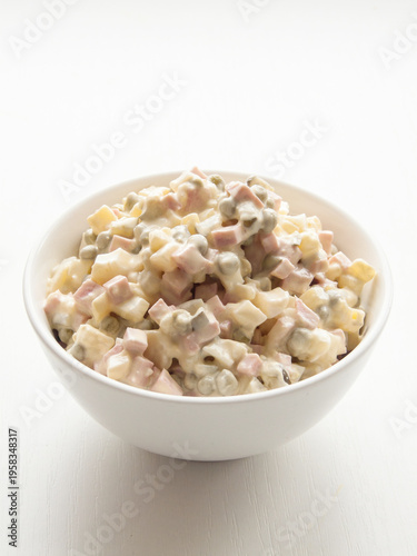 Bowl with traditional Olivier salad, classic dish made of veggies, meat covered in mayonnaise.